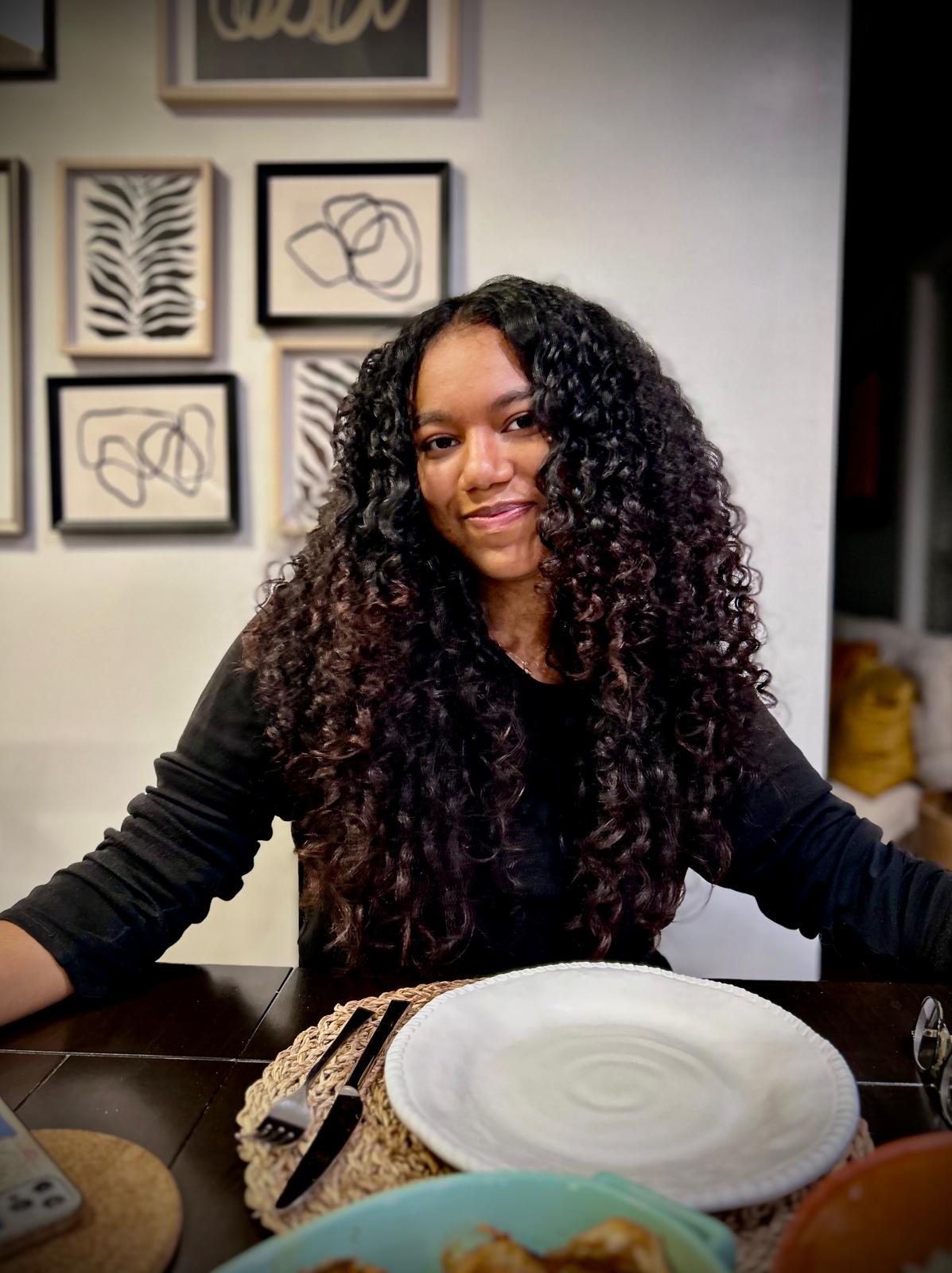 Mia at the dinner table, curls down, half a smile